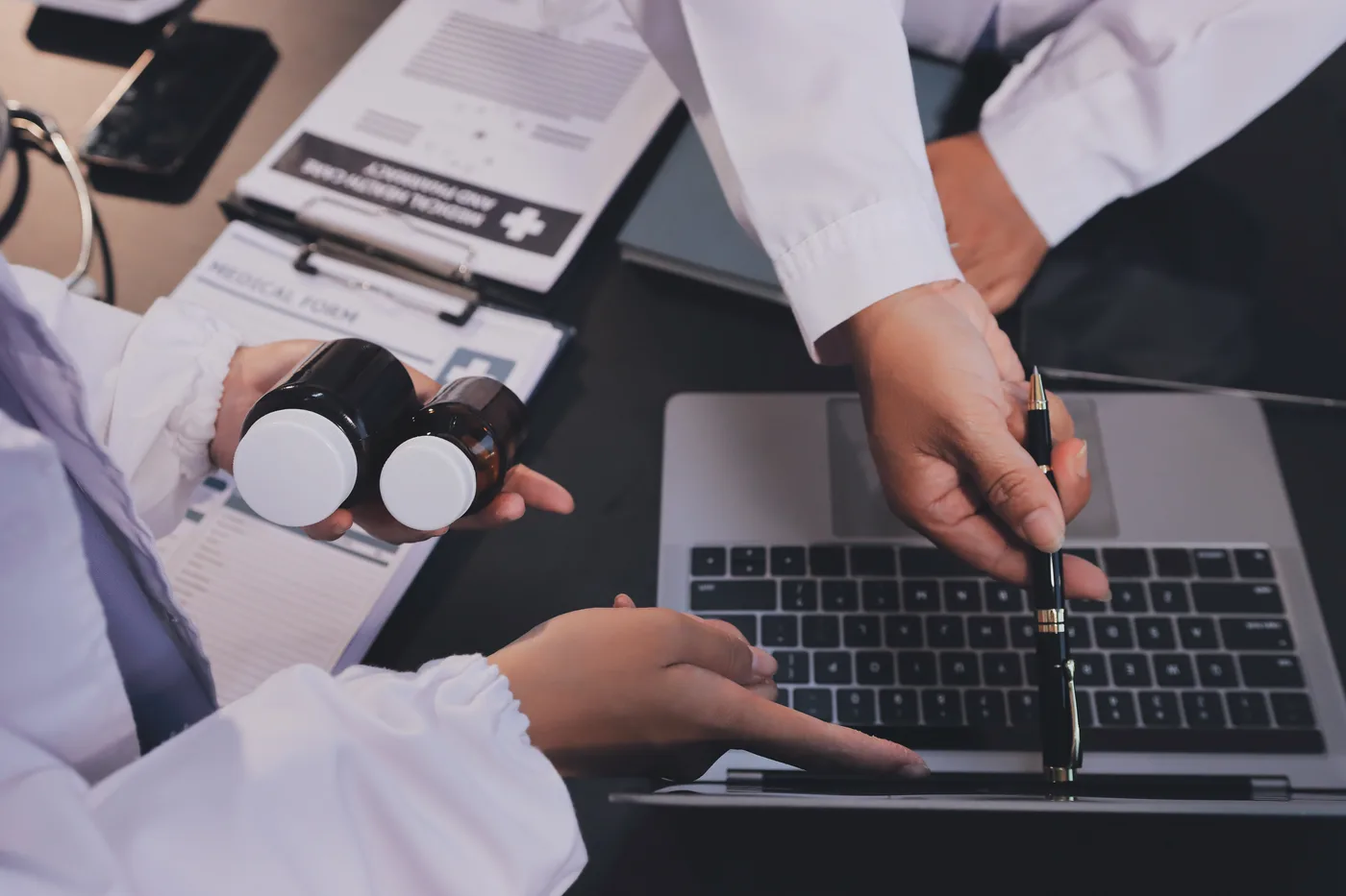 Clinician reviewing medication details beside a laptop