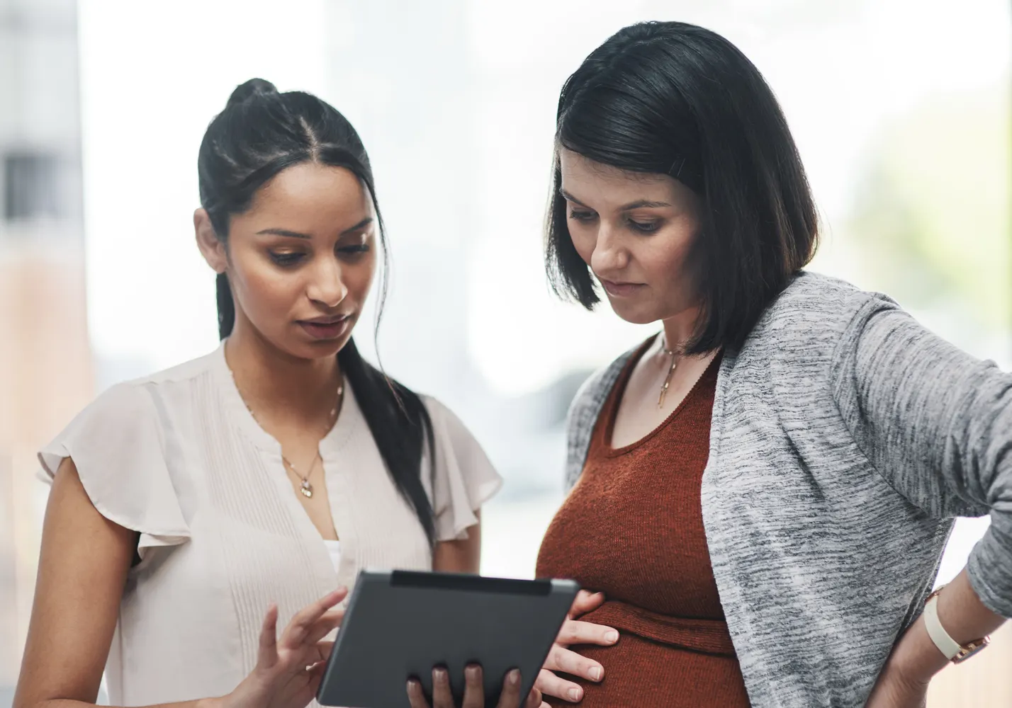 A pregnant patient reviewing information on a tablet with a care provider
