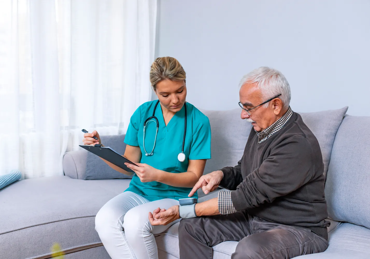 A nurse checking an older patient’s blood pressure at home